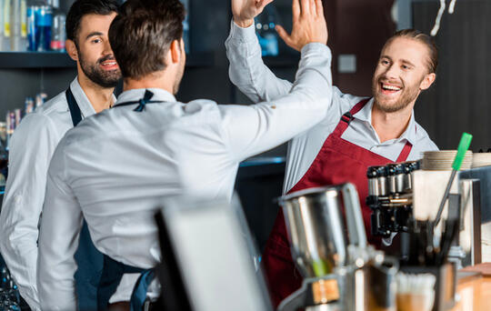 contratar a empleados camareros chocando palmas en restaurante